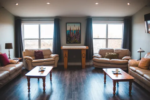 Lounge with sofas and armchairs beneath large windows.