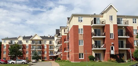Residence buildings with balconies and landscaped front gardens.