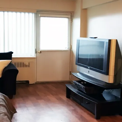 Room with a sofa, television and door beside a window