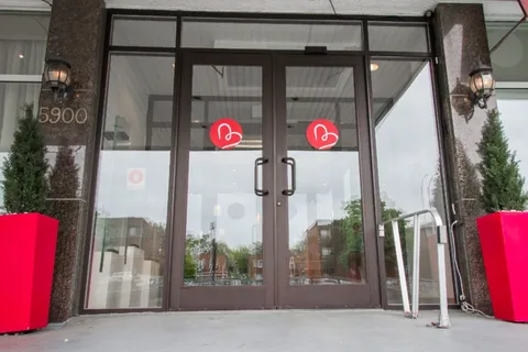 Glass entrance doors with red planters and the number 5900 beside them