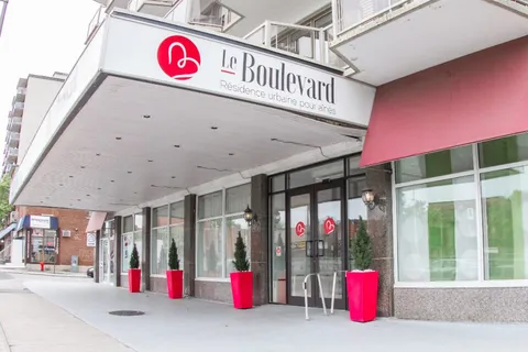 Covered entrance with glass doors and planters beside the building