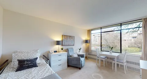 Studio suite with a bed, armchair, dresser and window seating.