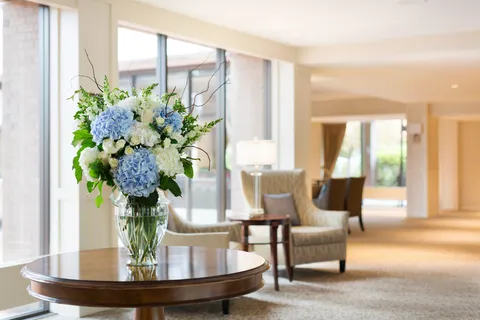 Reception area with a flower arrangement and seating beside windows.