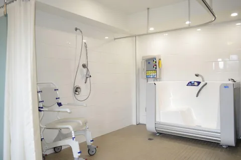 Tiled bathing room with an accessible tub, shower and wheeled shower chair