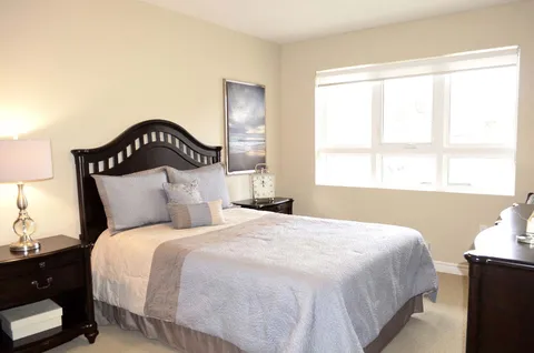 Bedroom with a dark wooden bed, bedside tables, lamps and a large window