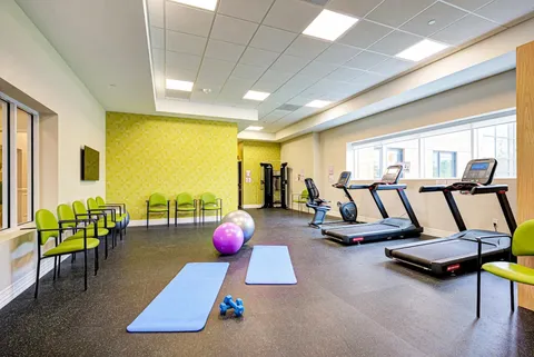 Fitness room with treadmills, exercise mats, dumbbells and green chairs