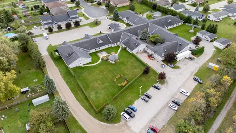 Aerial view of a low-rise building, parking areas, surrounding trees and lawns