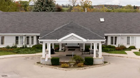 Low-rise building with a covered entrance, shrubs and a paved circular driveway