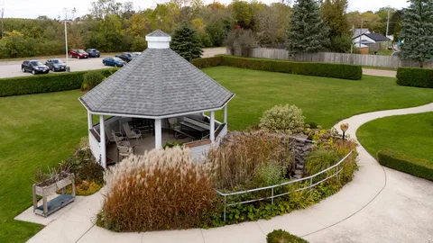 Garden with a wooden gazebo, paved paths, flowering borders and a lawn