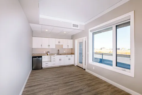 Empty room with a kitchenette, pale walls and a large window