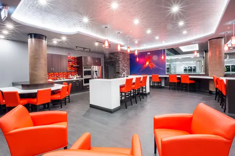 Room with red armchairs, small tables and a serving counter