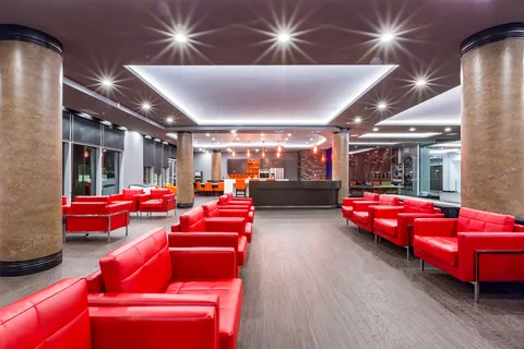 Lobby with red armchairs, glass walls and a wide corridor