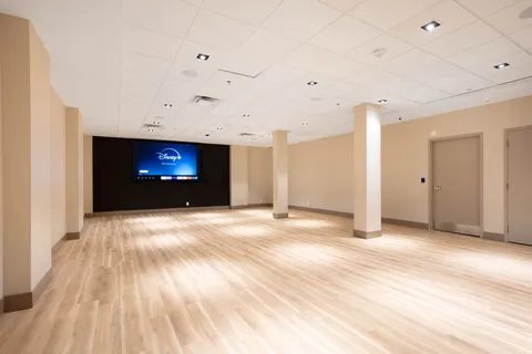 Empty room with a wood floor, square columns and a wall-mounted television