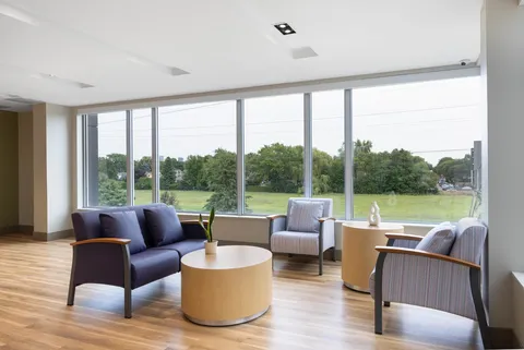 Seating area with a blue sofa, two armchairs and large windows overlooking trees