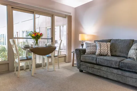 Suite sitting area with a sofa, table and sliding balcony doors.