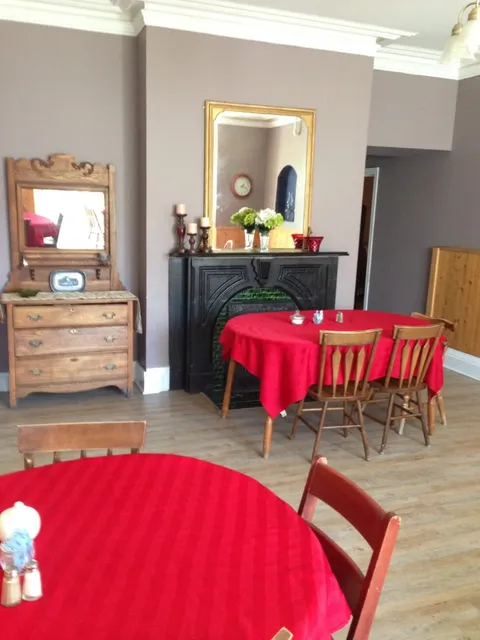 Dining room with red tablecloths, wooden chairs, mirrors and a fireplace