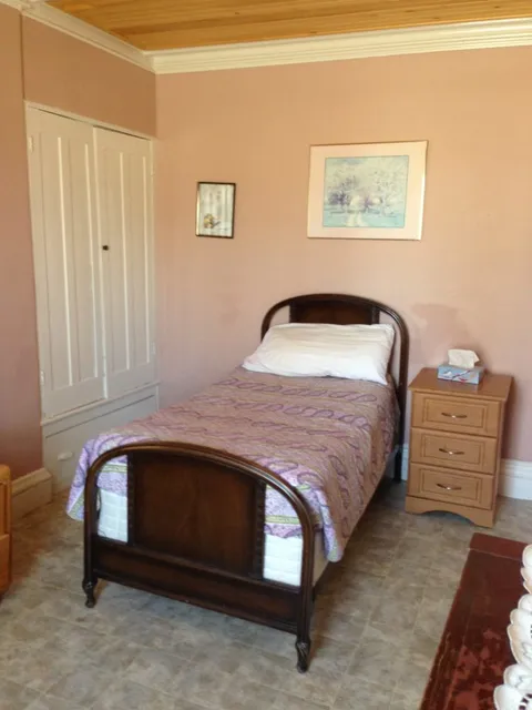 Bedroom with a single bed, purple bedspread, bedside cabinet and white closet doors