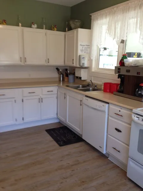 Kitchen with white cabinets, a double sink, dishwasher and stove