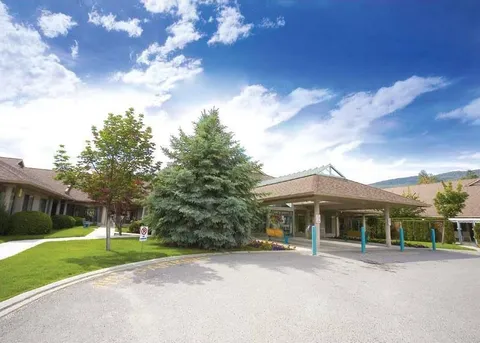 Residence entrance with a covered driveway, lawns and flowering trees