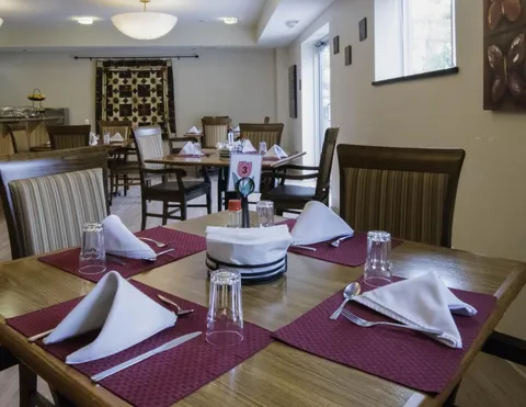 Dining tables with red placemats, folded white napkins and upholstered wooden chairs