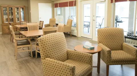 Room with upholstered chairs and wooden tables beside windows
