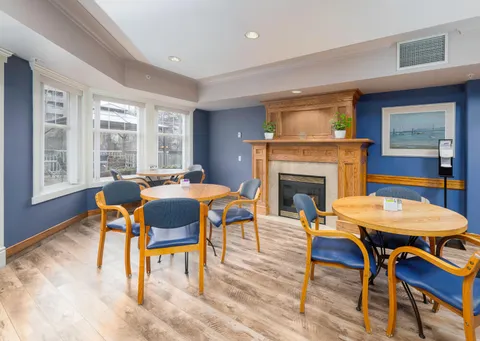 Tables and chairs beside a fireplace and windows.