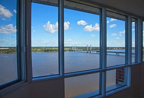 Large windows overlooking a river and a cable-stayed bridge