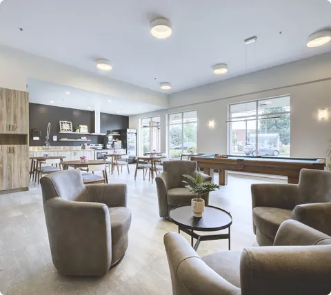 Lounge with armchairs and tables adjoining an open dining area.