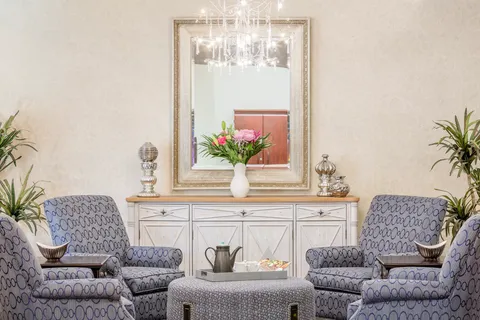Seating area with patterned armchairs, a mirror and a chandelier