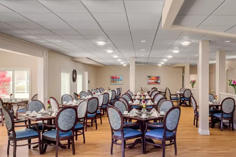 Dining room with set tables, blue chairs and landscape paintings