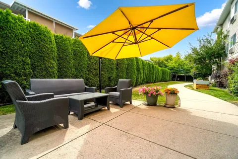 Patio seating under a yellow umbrella beside a lawn
