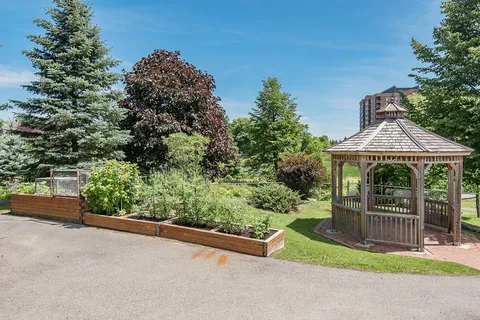 Gazebo beside raised garden beds and a paved path.