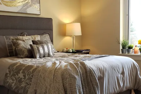Bedroom with a bed, nightstand and large window.