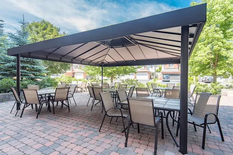 Patio tables and chairs beneath a wide metal canopy.