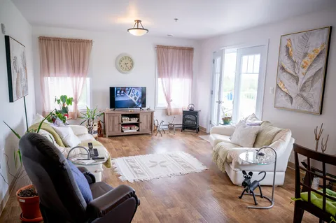 Furnished apartment living room with a television and balcony door.