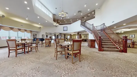 Room with wooden tables, chairs and a broad staircase