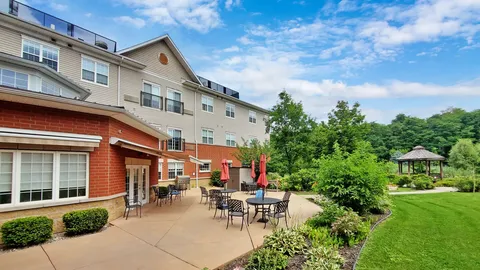 Brick residence wing beside a paved patio and chairs