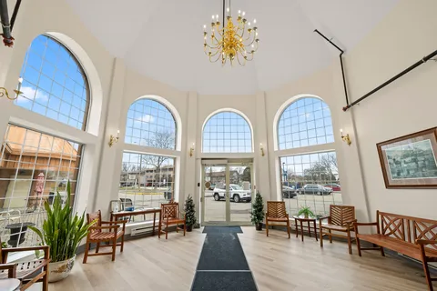 Entrance lobby with tall arched windows, wooden benches and a black floor mat