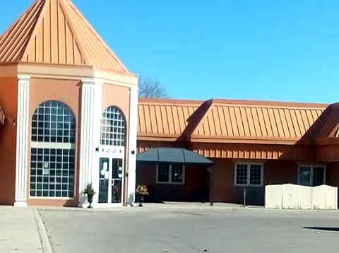 Brick residence with a tall arched window, copper-coloured roof and glass entrance doors