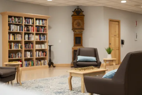 Library with armchairs, a bookcase, a coffee table and a tall clock