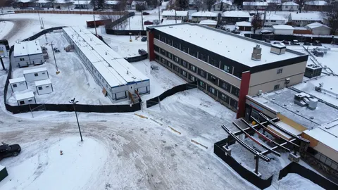 Residence building in winter with temporary buildings and snow-covered grounds.