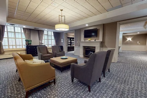 Lounge with armchairs, an ottoman, fireplace and television.