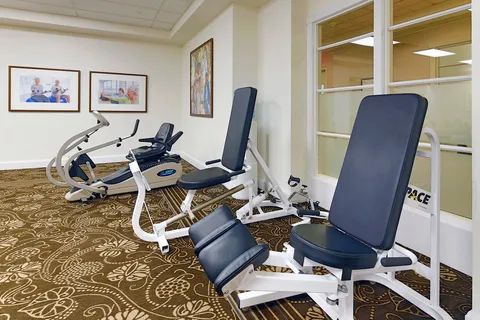 Fitness room with strength training machines and large windows.