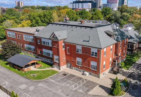 Aerial view of a three-storey red-brick building with a gazebo and parking spaces