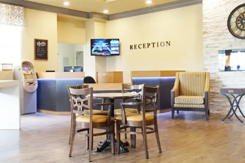 Reception area with a counter, a round table, chairs and a wall-mounted information screen