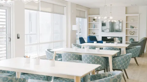 Room with tables, patterned chairs and a fireplace