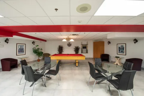Billiard room with a red-felt table, glass tables and black chairs