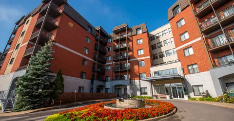 Residence wings with balconies around an entrance courtyard and flower beds