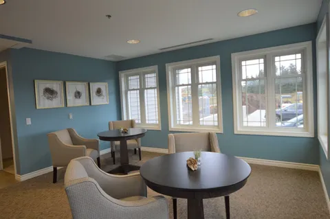 Room with armchairs and round tables beside large windows