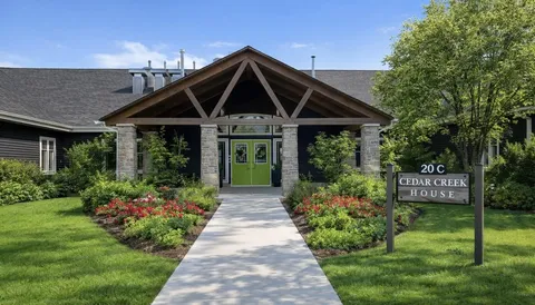 Single-storey building with a covered entrance, a paved path and flower beds